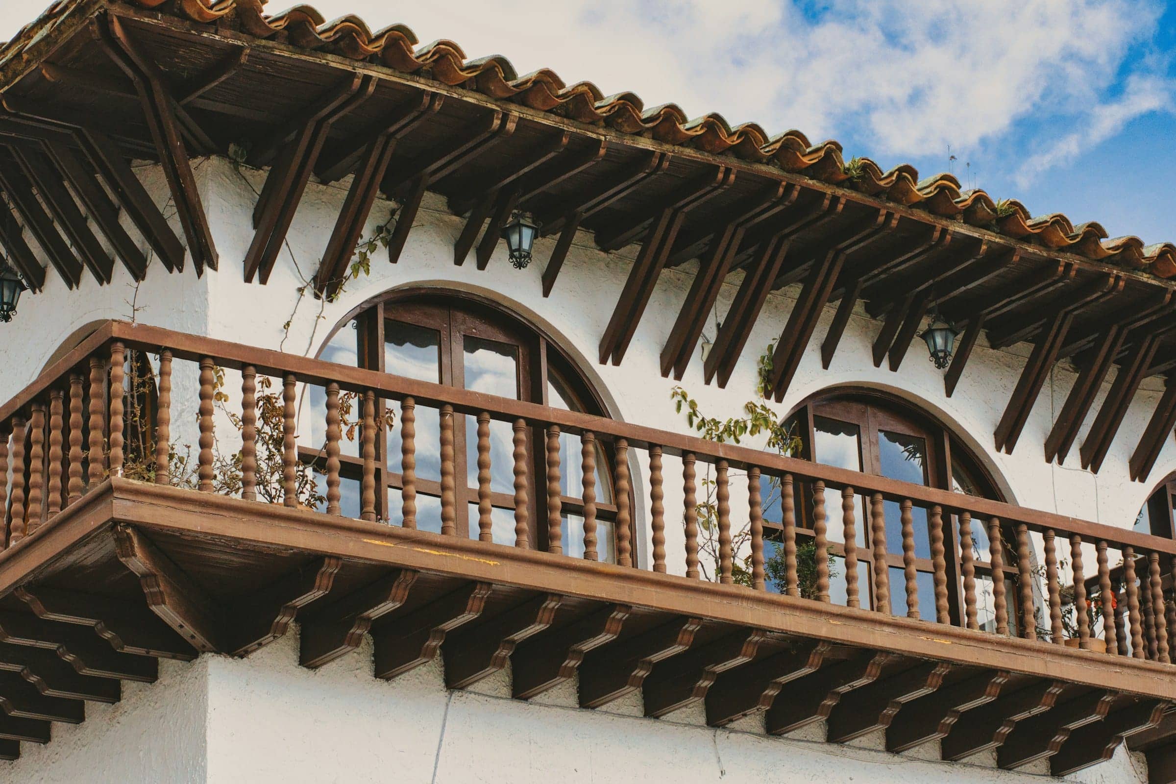 Carved wooden balcony and exposed rafters under a clay tile roof